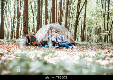 Senior Paar auf dem Campingplatz im Wald sitzen, weite Aussicht auf die Wälder Stockfoto