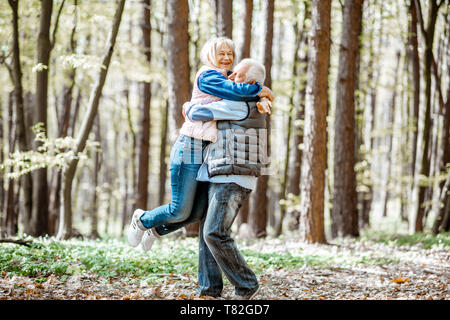 Gerne älteres Paar umarmen im Wald die Natur genießen und freie Zeit auf Ihren Ruhestand Stockfoto