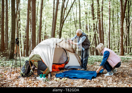 Senior paar Vorbereitung für die übrigen, die Verlegung der Hütte und Plaid im Wald Stockfoto