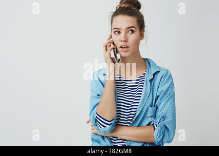 Hallo kann ich bestellen. Portrait von cute and good-looking modische Frau unordentlich hairbun beiseite schaut nachdenklich Holding Smartphone gedrückt Ohr Stockfoto