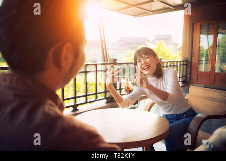 Schöne fröhliche asiatischen jüngere Frau ein Foto von smart phone mit Glück emotion Stockfoto