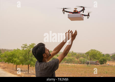 Konzept der Drohne Lieferung, junger Mann, der das Erzeugnis erhält, von Flying drone. Stockfoto