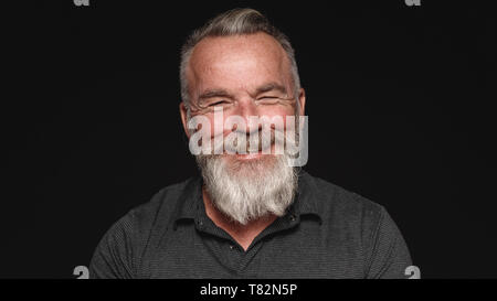 Nahaufnahme der lächelnden älteren Mann mit einem weißen Bart. Portrait eines älteren Mannes auf schwarzen Hintergrund isoliert. Stockfoto