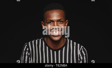 Nahaufnahme der lächelnden afrikanischen Mann an der Kamera schaut. Portrait der afrikanischen Mann auf schwarzem Hintergrund isoliert. Stockfoto