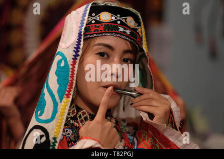 Junge usbekische Frau in traditionellen bestickten Kostümen im Surkhandarya-Stil, die Maultrommel spielt, die von den Turkvölkern in der Stadt Jarkurgan in Surkhandarya oder der Surxondaryo-Region in Usbekistan verwendet wird Stockfoto