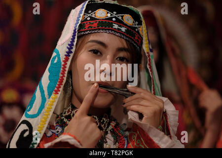 Junge usbekische Frau in traditionellen bestickten Kostümen im Surkhandarya-Stil, die Maultrommel spielt, die von den Turkvölkern in der Stadt Jarkurgan in Surkhandarya oder der Surxondaryo-Region in Usbekistan verwendet wird Stockfoto