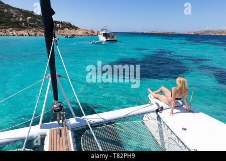 Frau entspannen im Sommer Segeln auf einem Katamaran in der Nähe von Bild perfekt weißen Sandstrand auf der Insel Spargi in Maddalena Stockfoto