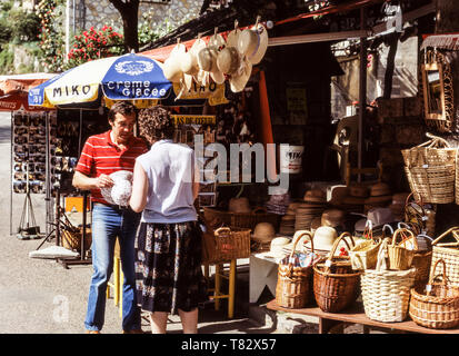 Britischer Tourist Kauf eines Sonnenhut aus einem Marktstand in der warmen und sehr sonnigen Region Provence in Frankreich. Stockfoto