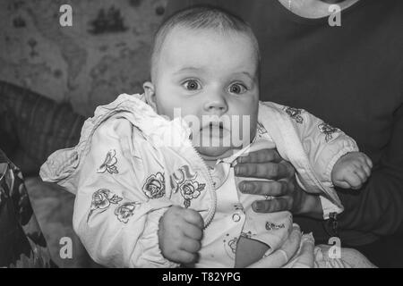 Porträt einer überrascht vier Monate altes Baby Mädchen in den Armen ihrer Mutter sitzen, Schwarz und Weiß Foto Stockfoto