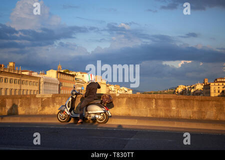 Überraschenden Schuß eines italienischen Mann trägt einen Helm mit italienischer Flagge neben seinem Roller ein Foto bei Sonnenuntergang in Florenz, Italien, ständigen Stockfoto