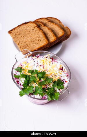 Traditionelle russische Layered betroot und Heringssalat (unter einem Pelzmantel) im Glas, weißer Hintergrund, selektiven Fokus. Stockfoto