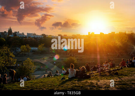 Berlin, Deutschland - April 2019: Personen, die Aussicht auf den Sonnenuntergang Himmel über Skyline von öffentlichen Park (Mauerpark) auf Summer Day in Berlin Stockfoto