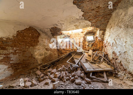 Alte verlassene leere Zimmer im Keller des alten Gebäudes oder Palace mit Gecrackten verputzte Ziegelwände, niedrige Decke, kleine Fenster mit und Müll auf Schmutz Stockfoto