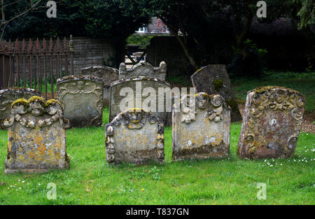 Alte Grabsteine in St. Johannes der Evangelist Kirchplatz, Taynton, Oxfordshire, England, Großbritannien Stockfoto