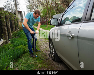 Jungen kaukasischen Mann Rad nach oben von Autos in der Nähe eines Hauses geparkt Stockfoto