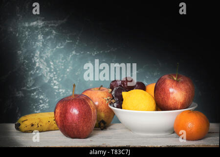 Noch immer leben Szene mit einige Früchte auf einem weißen Holzregal gegen einen dunklen Hintergrund. Leere Raum für Editor's Text Stockfoto