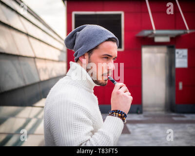 Junger Mann vaping, Rauchen E-Zigarette im Freien Stockfoto