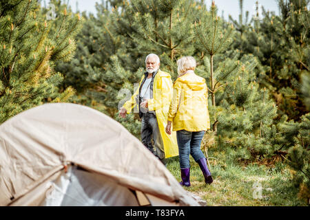 Senior Paar in gelben Regenjacken auf dem Campingplatz im Jungen Wald Stockfoto
