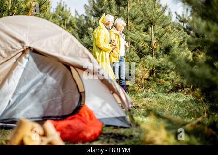 Senior Paar in gelben Regenjacken auf dem Campingplatz im Jungen Wald Stockfoto