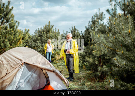 Senior Paar in gelben Regenjacken auf dem Campingplatz im Jungen Wald Stockfoto