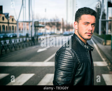 Junger Mann beim Überqueren einer Straße der Stadt, an der Kamera auf der Suche Stockfoto