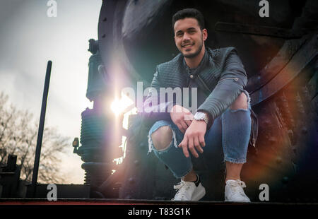 Junge Mann in schwarzem Leder Jacke in der Nähe von alten Zug Stockfoto