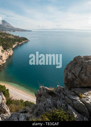 Felsige Küste mit Blick auf den kleinen versteckten Strand und blaues Meer in Kroatien am sonnigen Sommertag Stockfoto