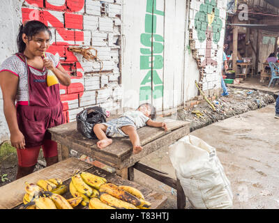 Belen, Iquitos, Peru - 27. März 2018: Junge Frau Verkauf von Bananen auf dem Markt in Belém Iquitos und das Kind schläft auf dem hölzernen Tisch. Belén Stockfoto