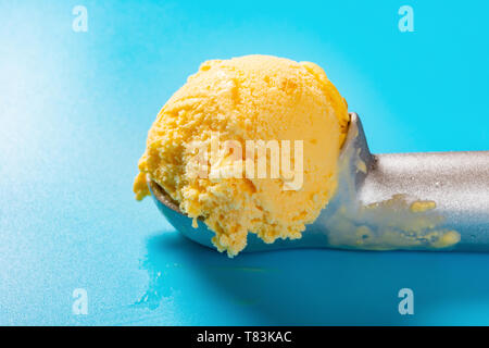 Löffel mit Mango geschmack Eis Ball auf blauem Hintergrund Nahaufnahme Stockfoto