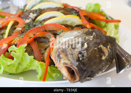 Essen von Fisch. Gebackene Karpfen. Fisch Diät. Fisch Kopf auf einem Teller Nahaufnahme Stockfoto