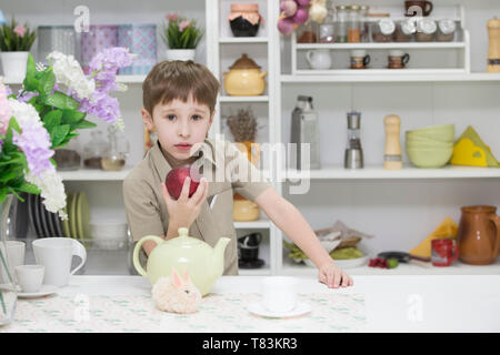 Junge in der Küche mit einem roten Apfel. ein Kind mit einer reifen Apfel. Gesundes Frühstück Stockfoto