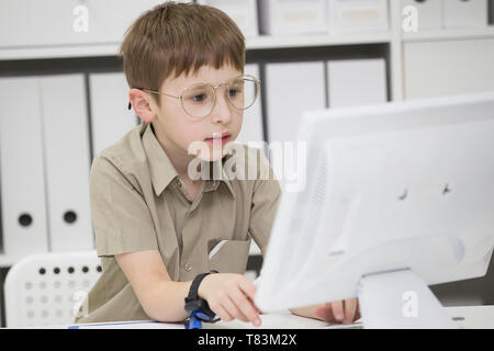 Ein Kind Mit Brille am Computer. Schüler sieht auf dem Monitor Stockfoto