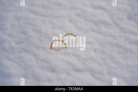 Zwei goldene Hochzeit Ringe in den frischen Schnee gelegt. Stockfoto