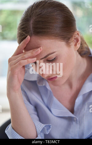Traurige junge Frau, die unter Depressionen leiden, mit Kopf in den Händen Stockfoto