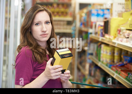 Portrait von Frau Kontrolle der Etikettierung von Lebensmitteln auf Box im Supermarkt Stockfoto