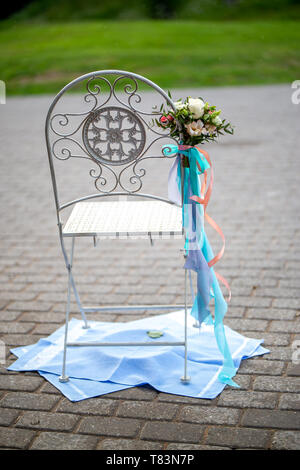 Stuhl mit Blumenstrauß und Bänder in Hochzeit Hochzeit stuhl ist auf Handtücher gebracht. Stockfoto