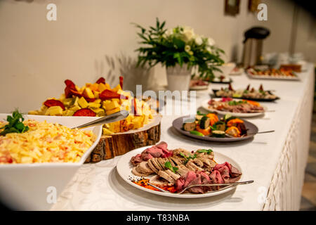 Fleischgericht und andere Snacks auf dem festlich gedeckten Tisch im Restaurant. Verschiedene Fleisch Snacks und andere Vorspeisen im Urlaub. Catering Hochzeit Tisch. Stockfoto