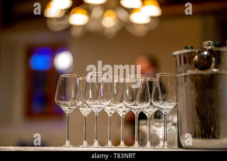 Leere Gläser, Weinflaschen und Eimer mit Eis am Tisch im Restaurant. Eiskübel, Wein Gläser und Flaschen auf dem Tisch arrangiert für Hochzeit Rezept Stockfoto