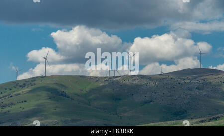 Landschaft mit weißen Wolken und Windenergieanlagen. Windräder entlang der Weise auf dem Hügel. Stockfoto
