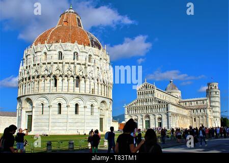 Touristen, die in das Baptisterium, Dom und Schiefer Turm von Pisa, Italien, Oktober 2018. Stockfoto