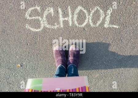 Das Wort Schule auf dem Asphalt und die Füße der Schüler. Zurück zur Schule Stockfoto