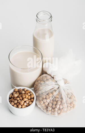 Kichererbse in Schüssel und Gaze in der Nähe von vegan Kichererbse Milch in Glas und Flasche auf grauem Hintergrund Stockfoto