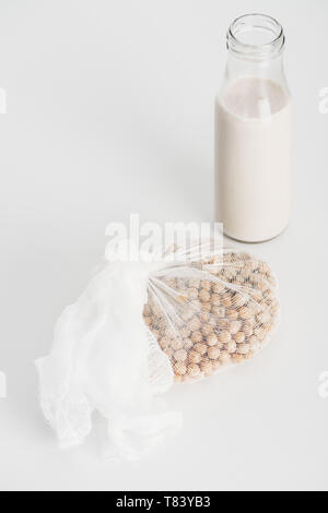 Kichererbsen in Weiß Gaze in der Nähe der Flasche mit vegan Kichererbse Milch auf grauem Hintergrund Stockfoto