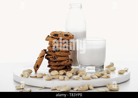 Vegan cashew Milch in Glas und Flasche in der Nähe von Schokolade Cookies isoliert auf weißem Stockfoto