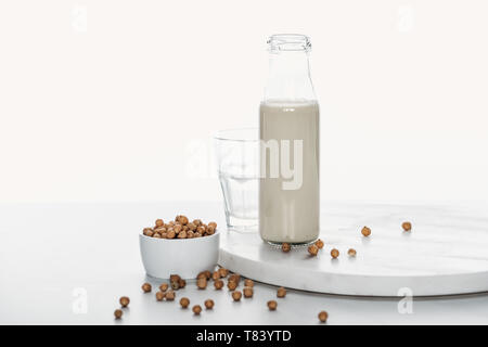 Kichererbse Milch in der Flasche in der Nähe von Kichererbse in Schale und leeren Glas isoliert auf weiss Stockfoto