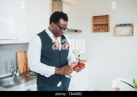 Geschäftsmann mit Smartphone in der Küche Stockfoto