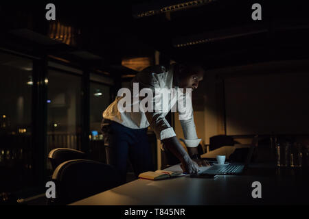 Junge Unternehmer in Büro in der Nacht Blick auf Laptop Stockfoto