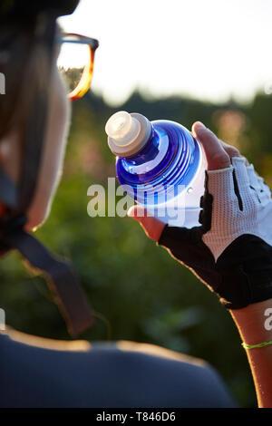 Weibliche Radfahrer Trinken aus der Flasche Wasser, über die Schulter sehen 7/8 Stockfoto