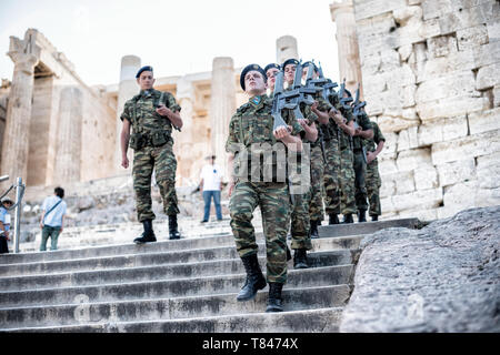 ATHEN, Griechenland – griechische Soldaten marschieren auf der Akropolis in Bildung. Die antike Akropolis erhebt sich auf dem felsigen Hügel und dominiert die Skyline von Athen, Griechenland. Das Parthenon mit seinen berühmten Säulen und Giebel ist das Herzstück dieses UNESCO-Weltkulturerbes. Umgeben von anderen klassischen Bauten, darunter dem Erechtheion und dem Tempel der Athena Nike, verkörpert diese Zitadelle aus dem 5. Jahrhundert v. Chr. den Ruhm der antiken griechischen Zivilisation und Architektur. Stockfoto