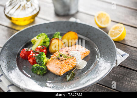 Gebratenes Lachsfilet broccoli Tomaten und Bratkartoffeln mit Dill Sauce Stockfoto